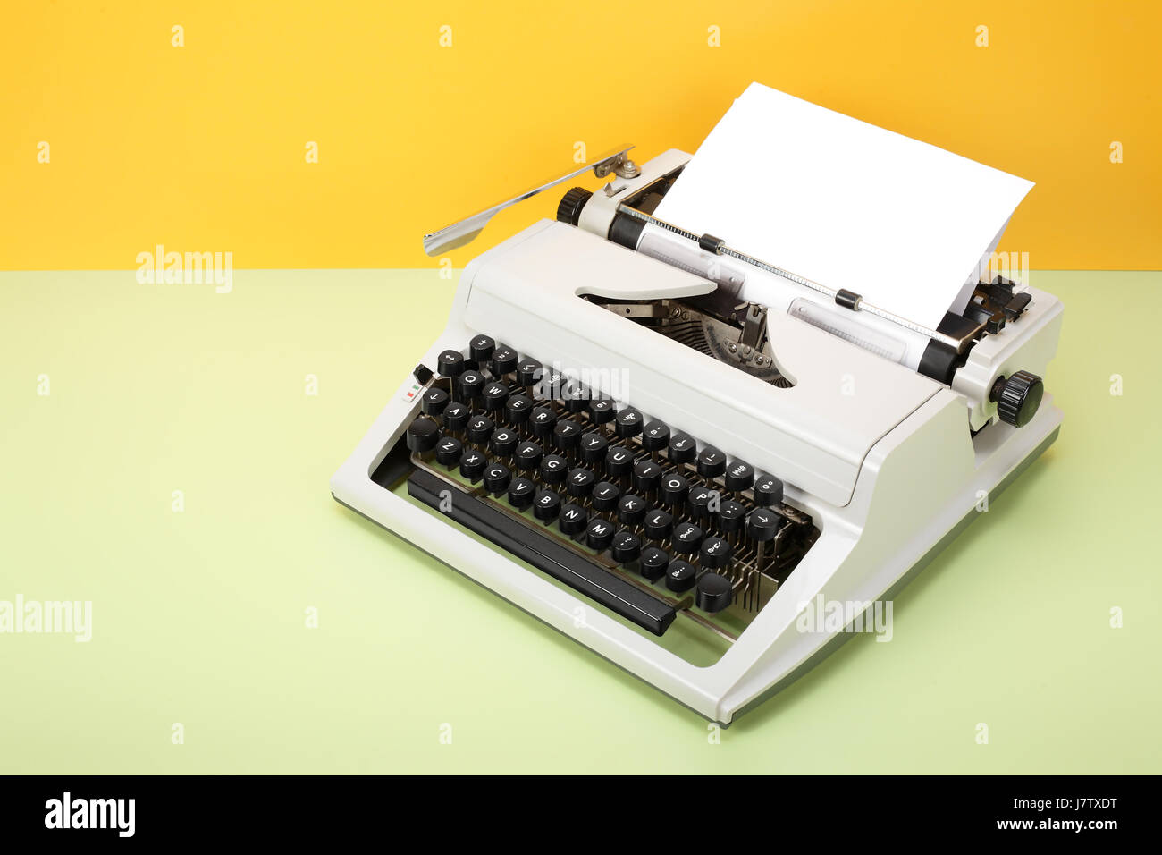 Objets Vintage Retro - Machine à écrire sur un fond jaune et un tableau vert. Banque D'Images