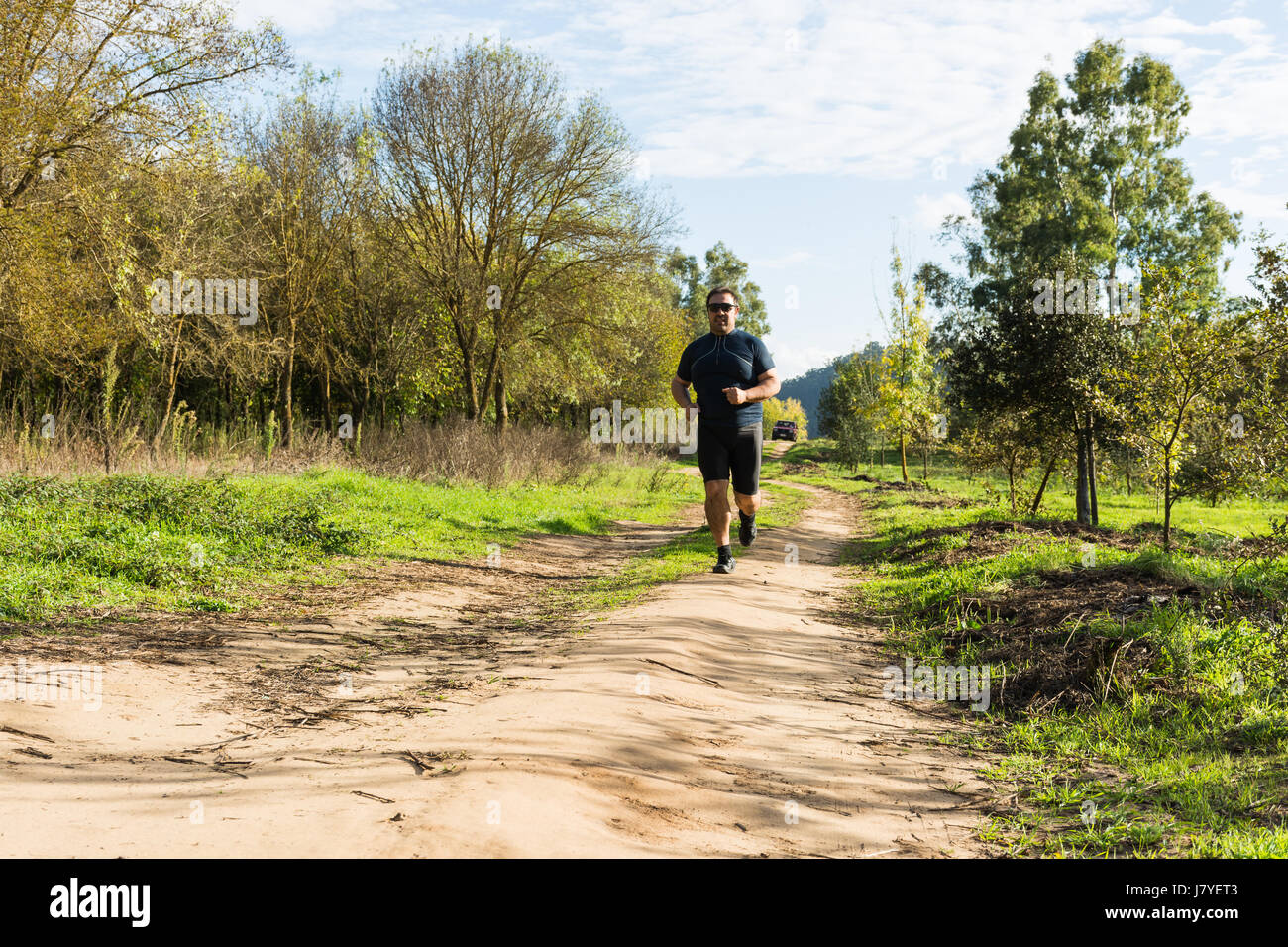 Gros Ventre man jogging , l'exercice de cardio, de faire dans le parc , un léger embonpoint, veulent perdre du poids. Sur une pelouse d'herbe verte entre les arbres sans lea Banque D'Images