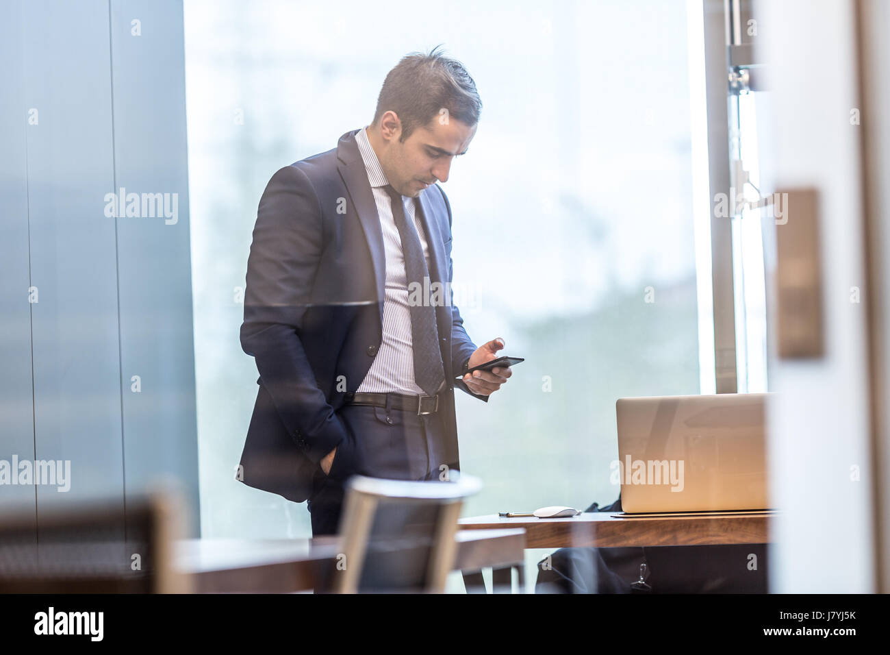 Businessman looking at smart phone in modern bureau d'entreprise. Banque D'Images