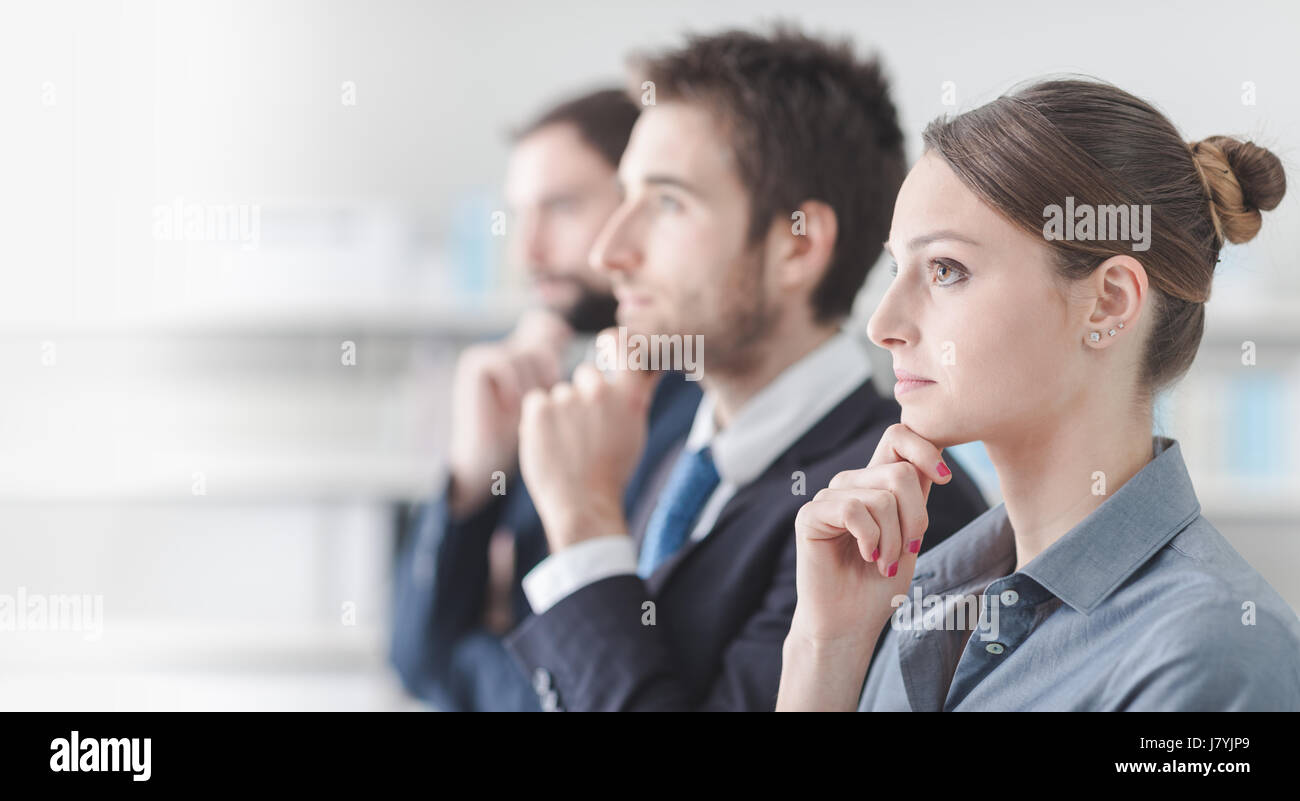 Certains gens d'affaires ciblées lors du séminaire, ils sont à l'écoute with hand on chin Banque D'Images Certains gens d'affaires ciblées lors du séminaire, ils sont à l'écoute with hand on chin Banque D'Images
