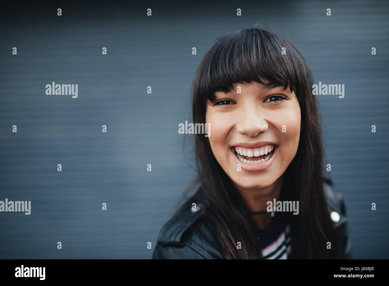 Close up portrait of young woman laughing contre fond gris. Belle hispanique modèle féminin s'amusant à l'extérieur. Banque D'Images