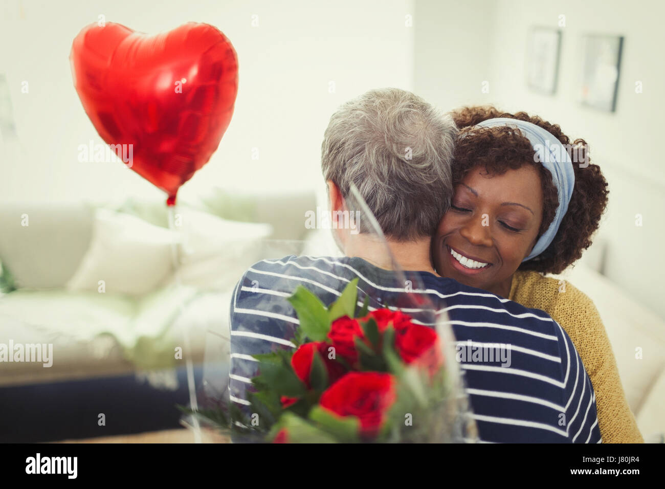 Femme serrant mari donnant Saint Valentin bouquet de roses et de ballon Banque D'Images