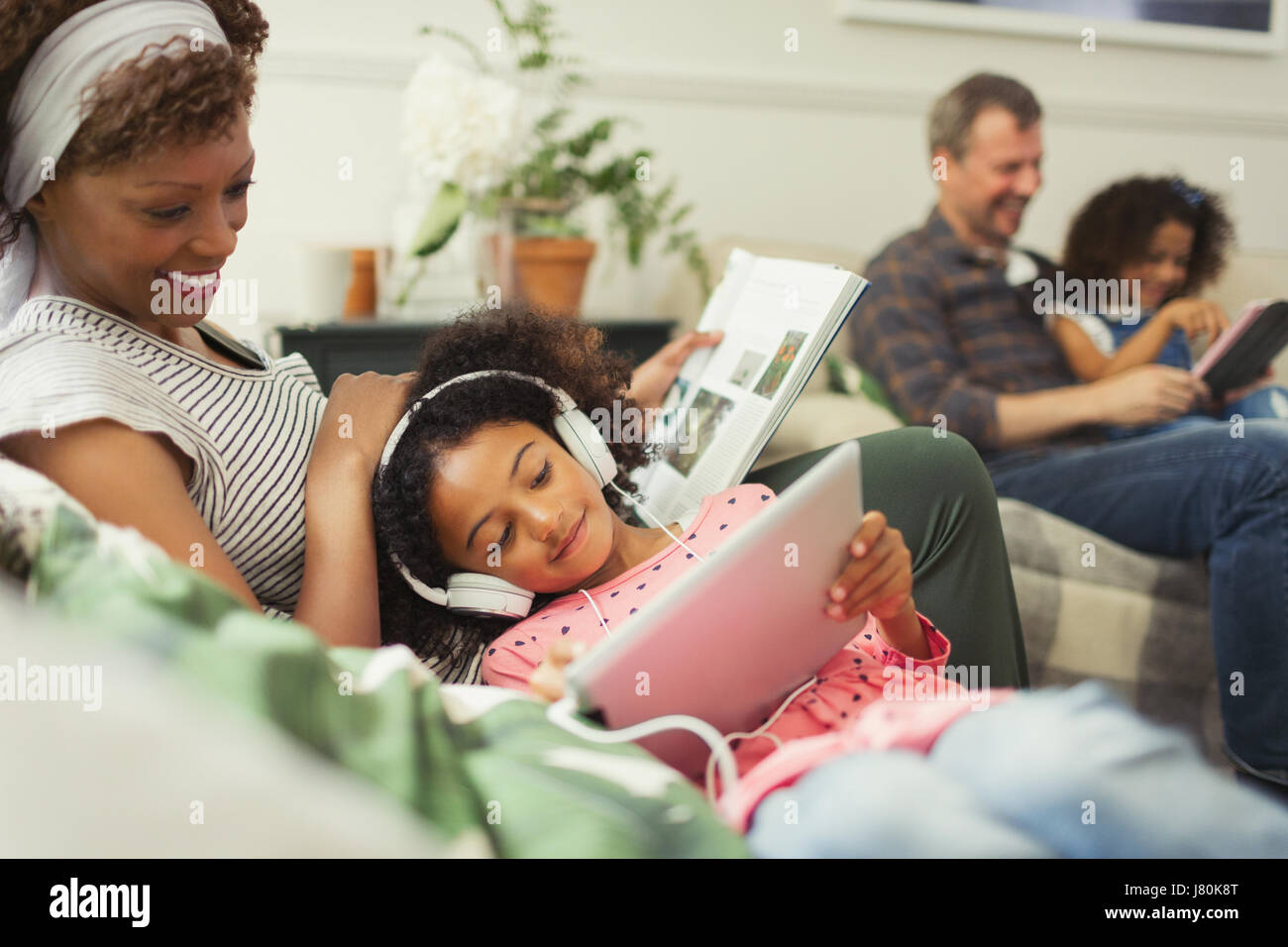 Mère Fille de câlins avec des écouteurs using digital tablet Banque D'Images