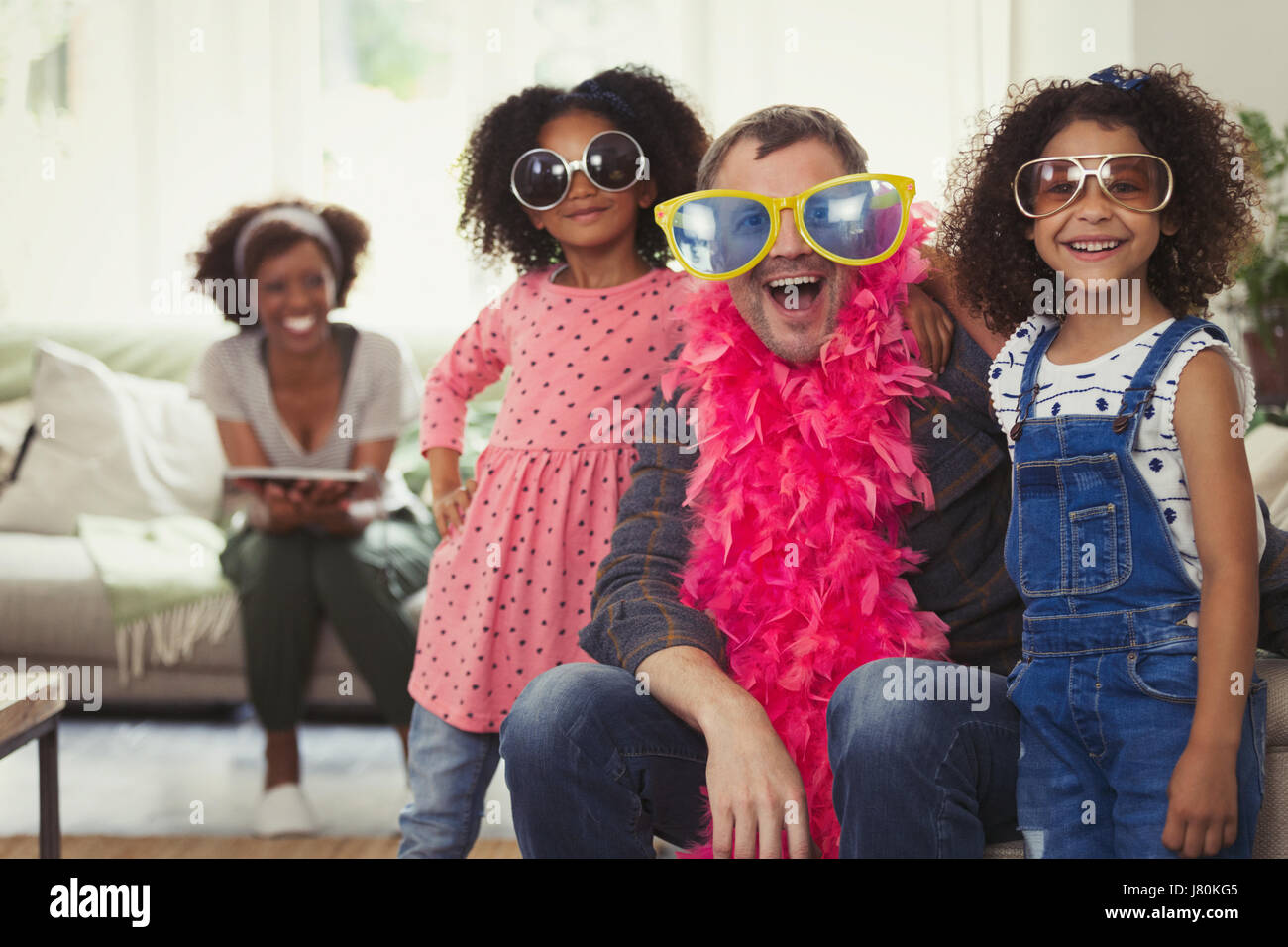 Espiègle portrait père multi-ethnique et des filles à l'habiller avec des lunettes de soleil et des boas en plumes Banque D'Images