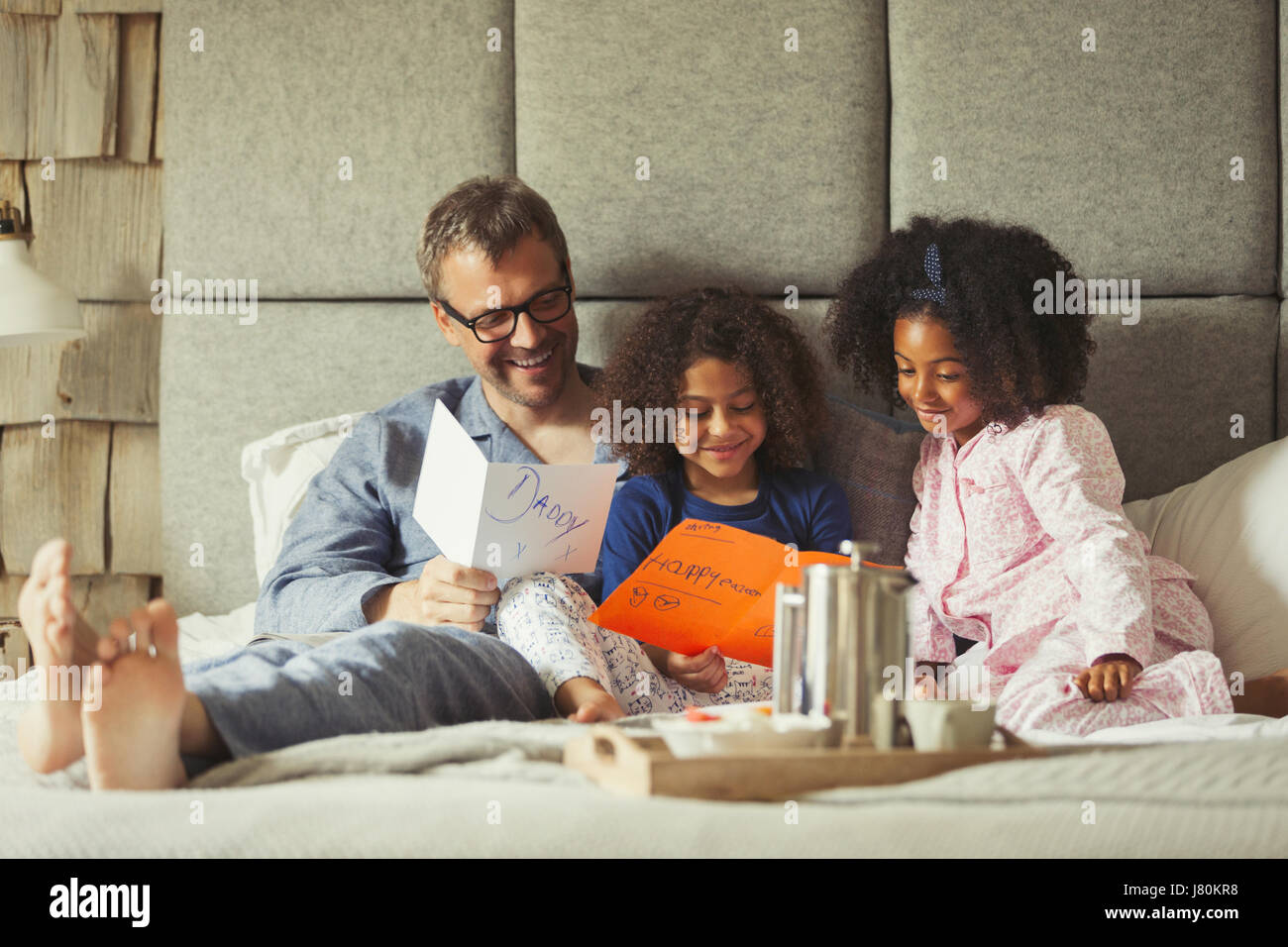 Filles multi-ethnique des cartes donnant au père sur le lit de la Fête des Pères Banque D'Images