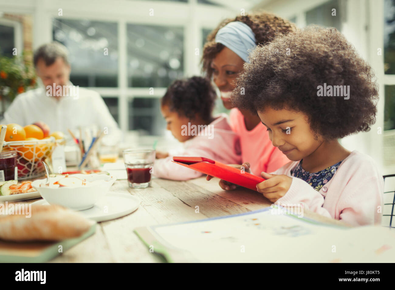 Girl using digital tablet at breakfast table Banque D'Images