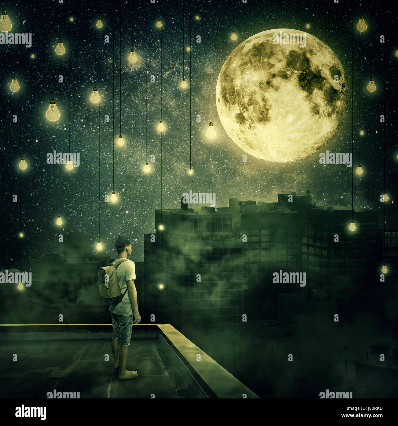 Jeune garçon rester sur le toit en regardant la pleine lune. Nuit Mystérieuse avec ampoules suspendues comme des étoiles sur la ville de brouillard Banque D'Images