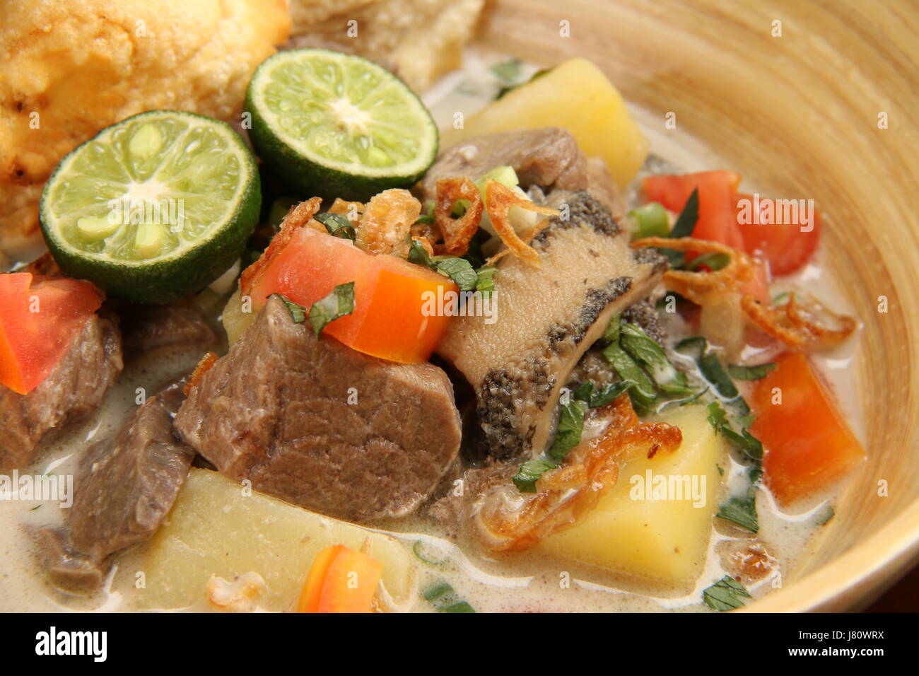 Soto Betawi populaires, la viande dans le lait de coco soupe de Jakarta. Servi avec tomate, céleri, oignon vert, échalotes, pirate, et de la chaux. Banque D'Images