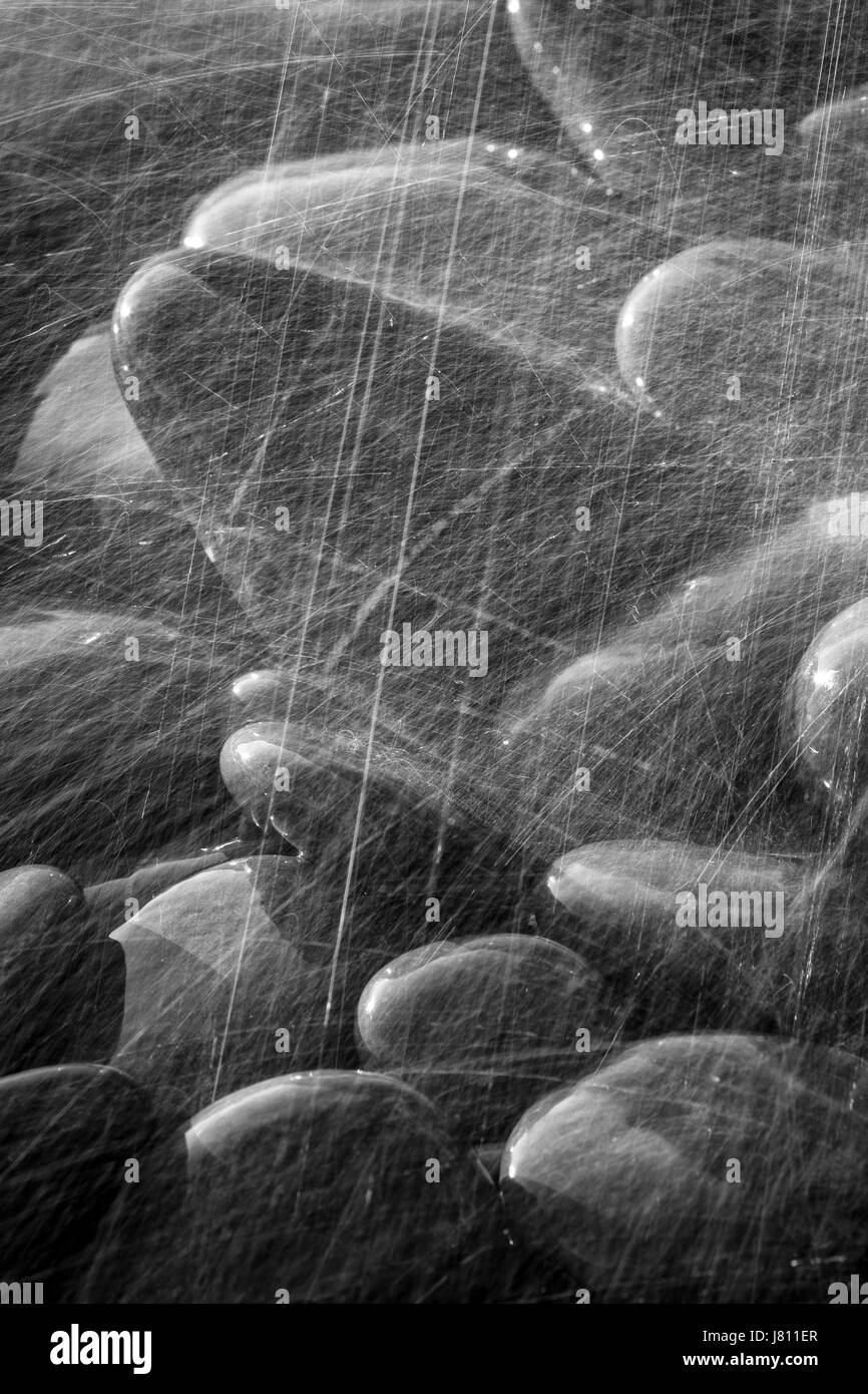 Rochers lisses au bas de la chute d'eau reflètent la lumière comme des gouttes d'eau rebondissent sur eux de créer des textures intéressantes et les modèles Banque D'Images