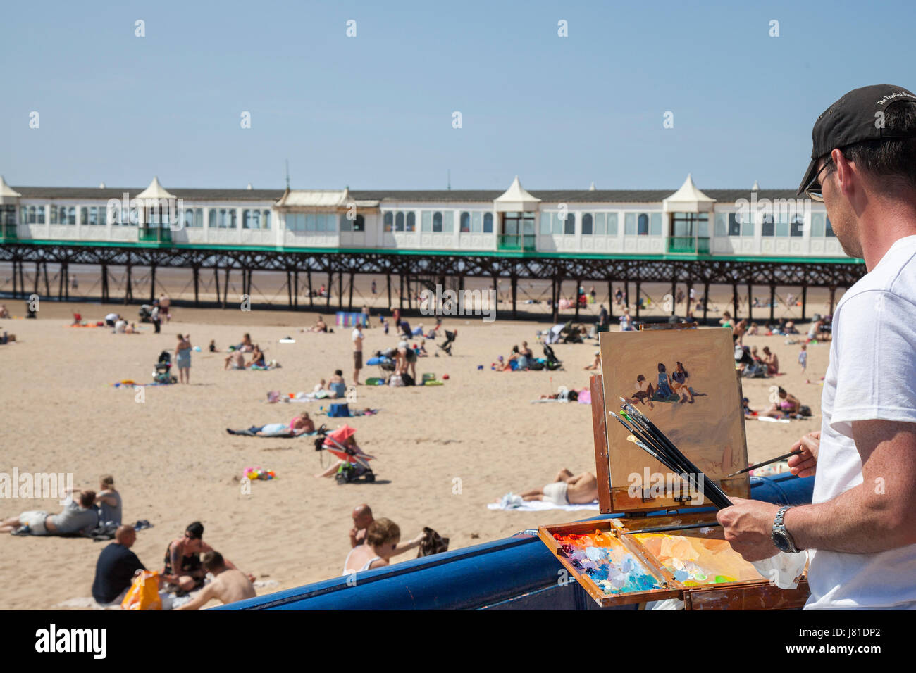 Lytham St Annes on Sea, Lancashire. Météo britannique. Paysagiste Norman Long 'peint la scène' sur la plage de Fylde comme foules affluent vers la jetée et resort zone front de mer pour profiter de l'ensoleillement d'été côtières près de Blackpool. Artiste de l'année en gagnant 2013 Norman a ouvert son premier one man show de Londres, la vie en ville, à Osborne Studio Gallery. Cette région rurale côtière Lancashire que gem est Lytham St Anne's Sandy Beach, qui abrite d'âne, une jetée victorienne et des aires de jeux pour enfants, à l'endroit idéal pour saisir l'essence de la station balnéaire. /AlamyLivenews MediaWorldImages crédit ; Banque D'Images