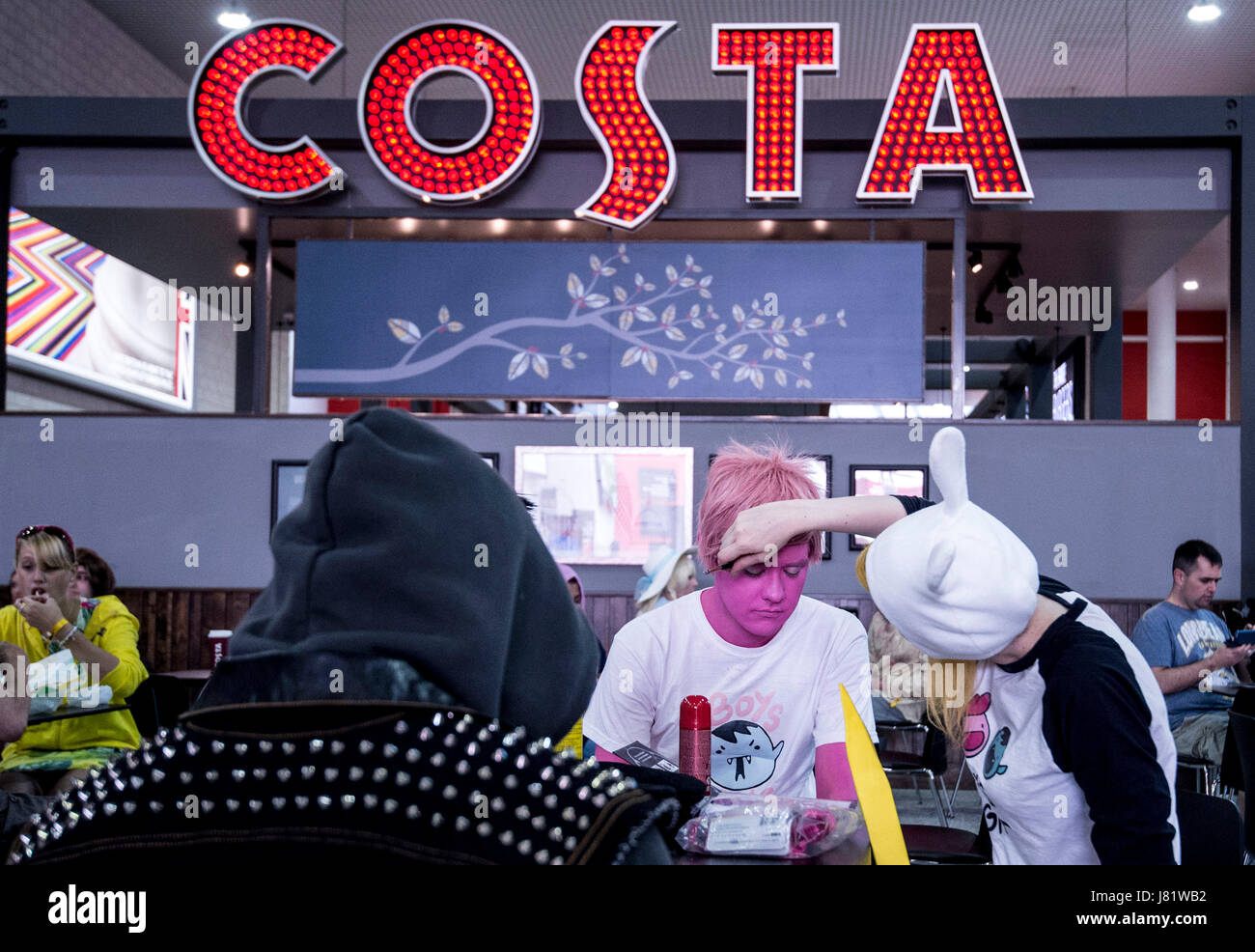 EDITORIAL Utilisez uniquement un homme a son visage peint en rose dans un café pendant la MCM London Comic Con à ExCel London. Banque D'Images