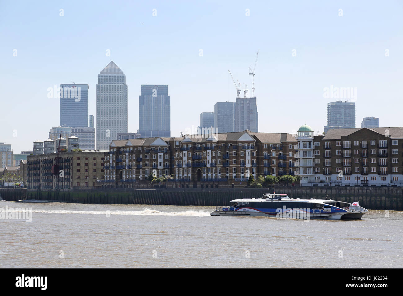 Un bus de la rivière Thames Clipper voyages en amont le long de la Tamise à Rotherhithe à Londres, au Royaume-Uni. Canary Wharf en arrière-plan. Banque D'Images