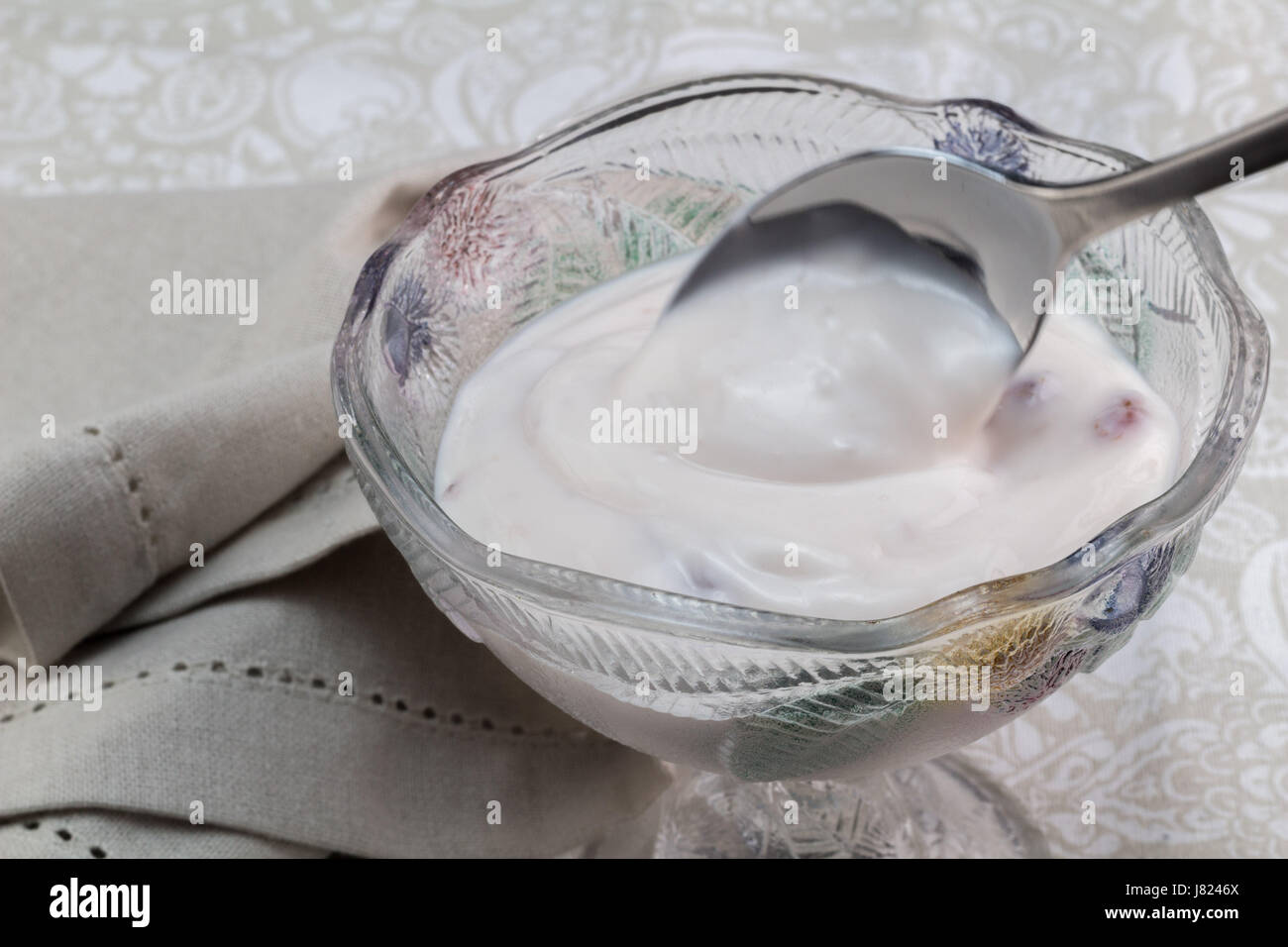 Yaourt grec naturel aux fruits rouges mélangés dans l'intestin en verre avec de belles nappes - nourriture de fond avec du yaourt crémeux sur spoon Banque D'Images