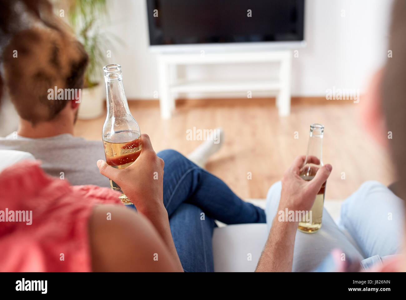 Les amis de boire une bière et regarder la télé à la maison Banque D'Images