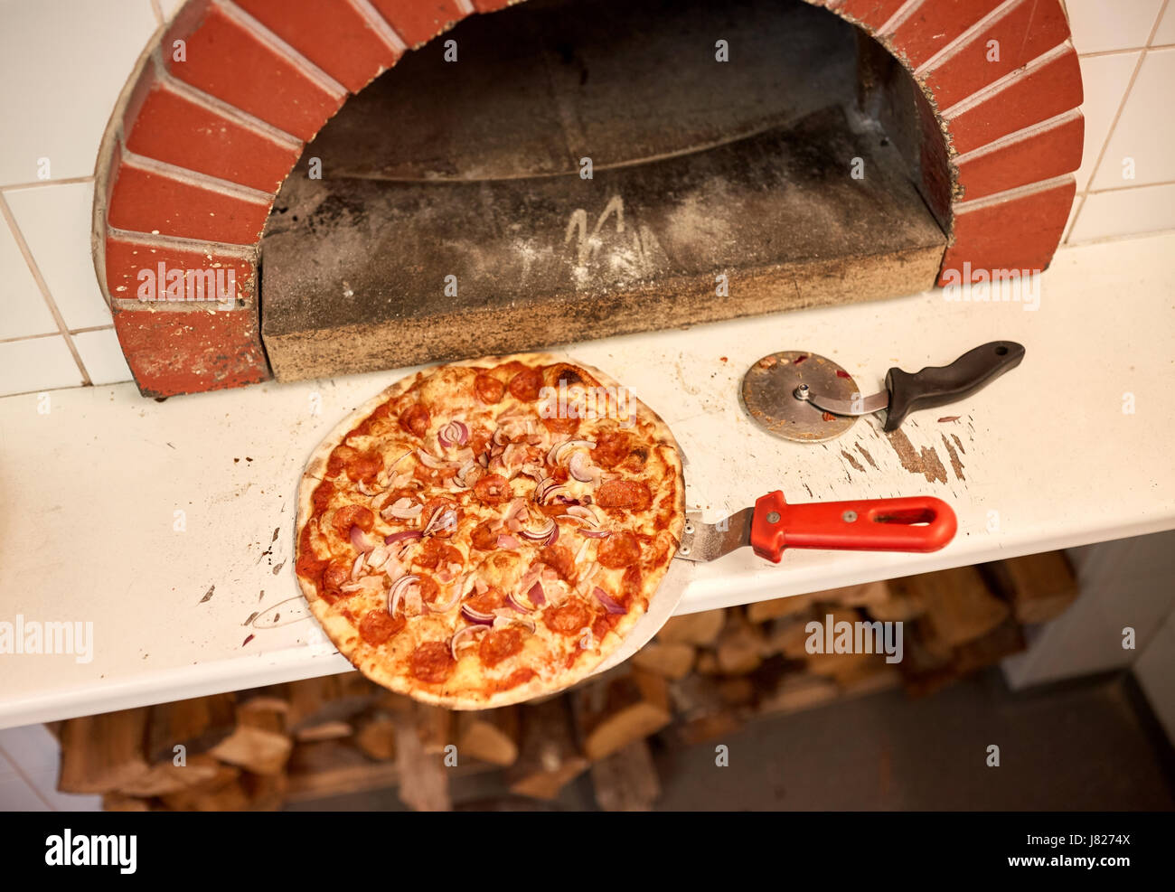 Sur pizza cuite sur Peel et la faucheuse à la pizzeria Four Banque D'Images Sur pizza cuite sur Peel et la faucheuse à la pizzeria Four Banque D'Images