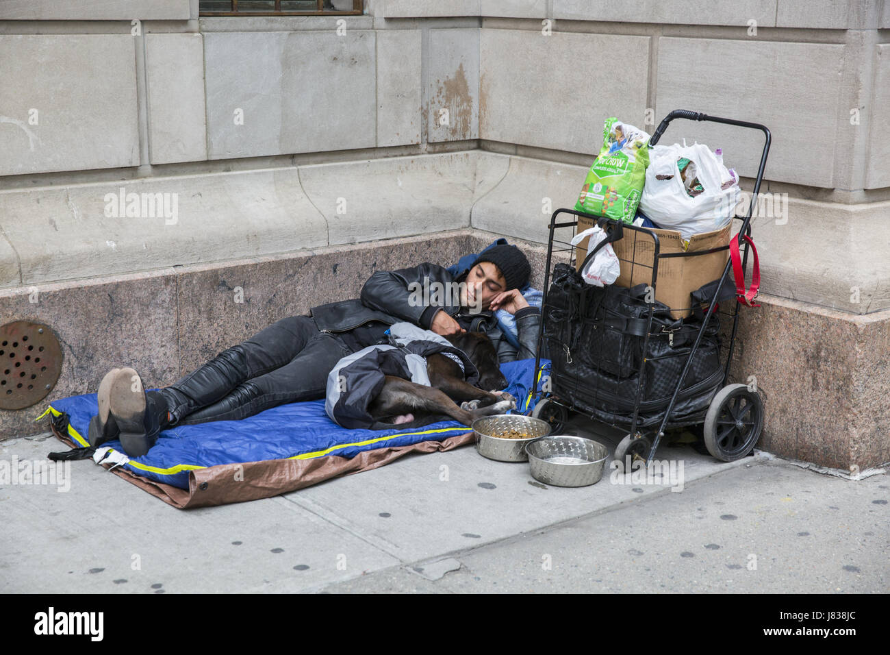 Sans-abri dort sur le trottoir avec son chien bien entretenu dans le centre de Manhattan. NYC Banque D'Images