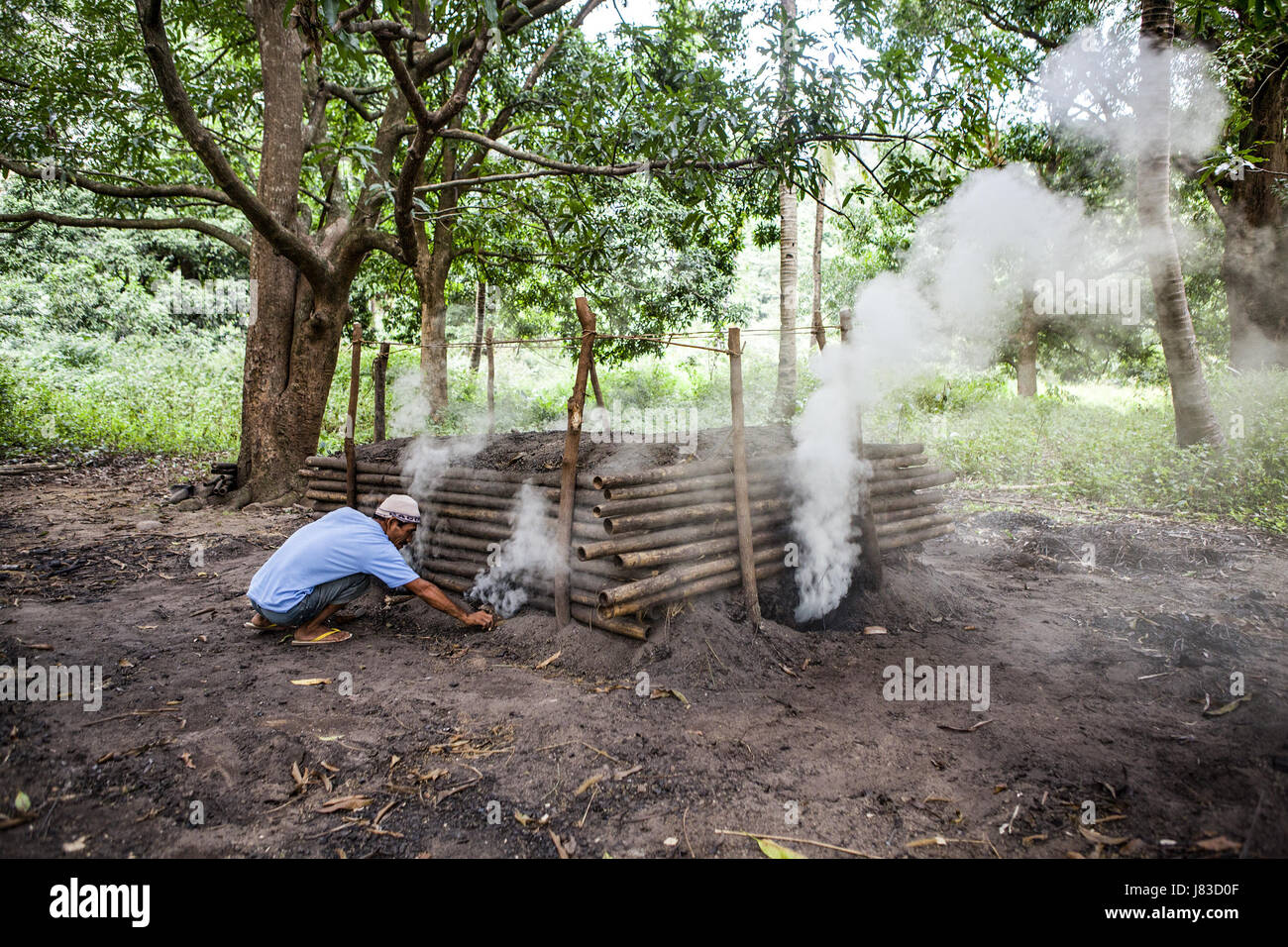 Un homme fait du charbon de bois dans son home-made four à Subic, l'île de Luzon, aux Philippines. Banque D'Images