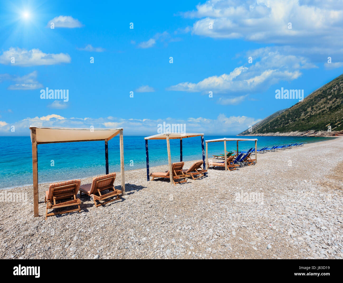 Plage ensoleillée d'été avec l'eau marine, soleil et nuages dans le ciel bleu azur (Albanie). Banque D'Images