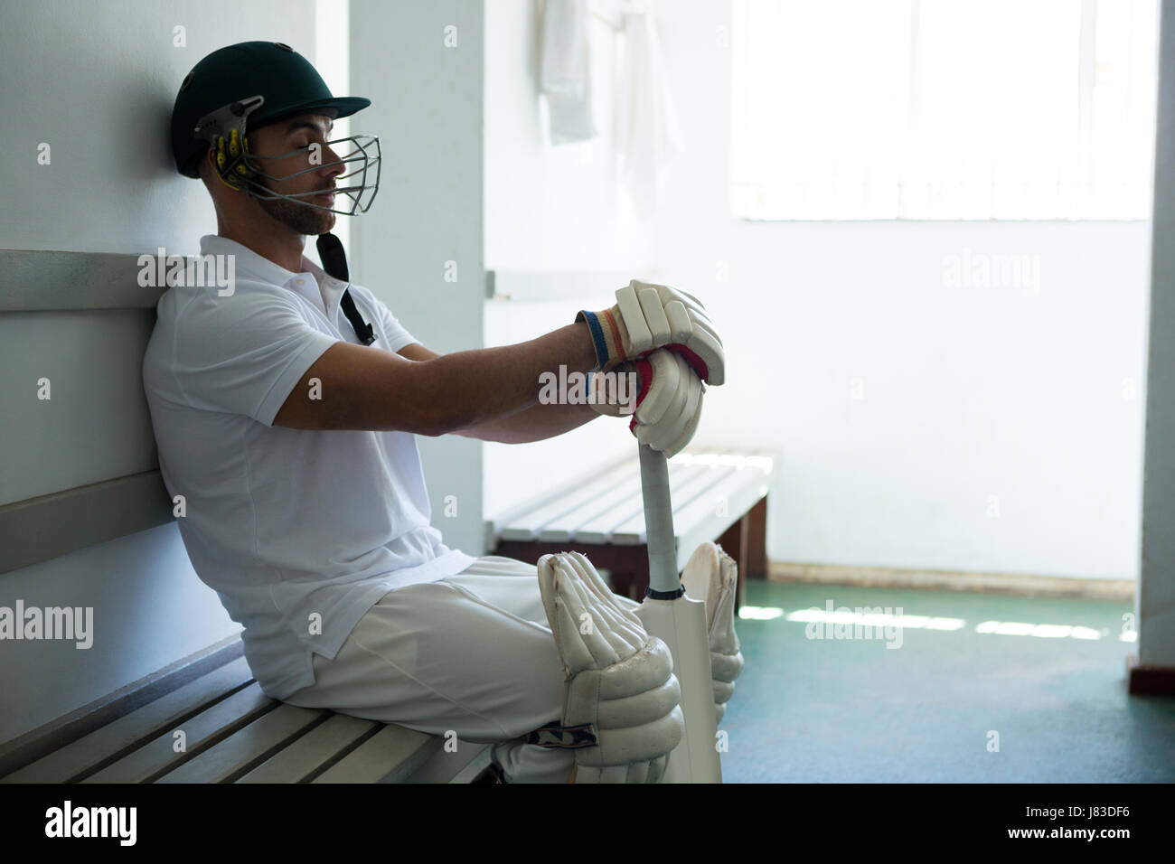 Close up de joueur de cricket assis sur un banc au vestiaire. Banque D'Images