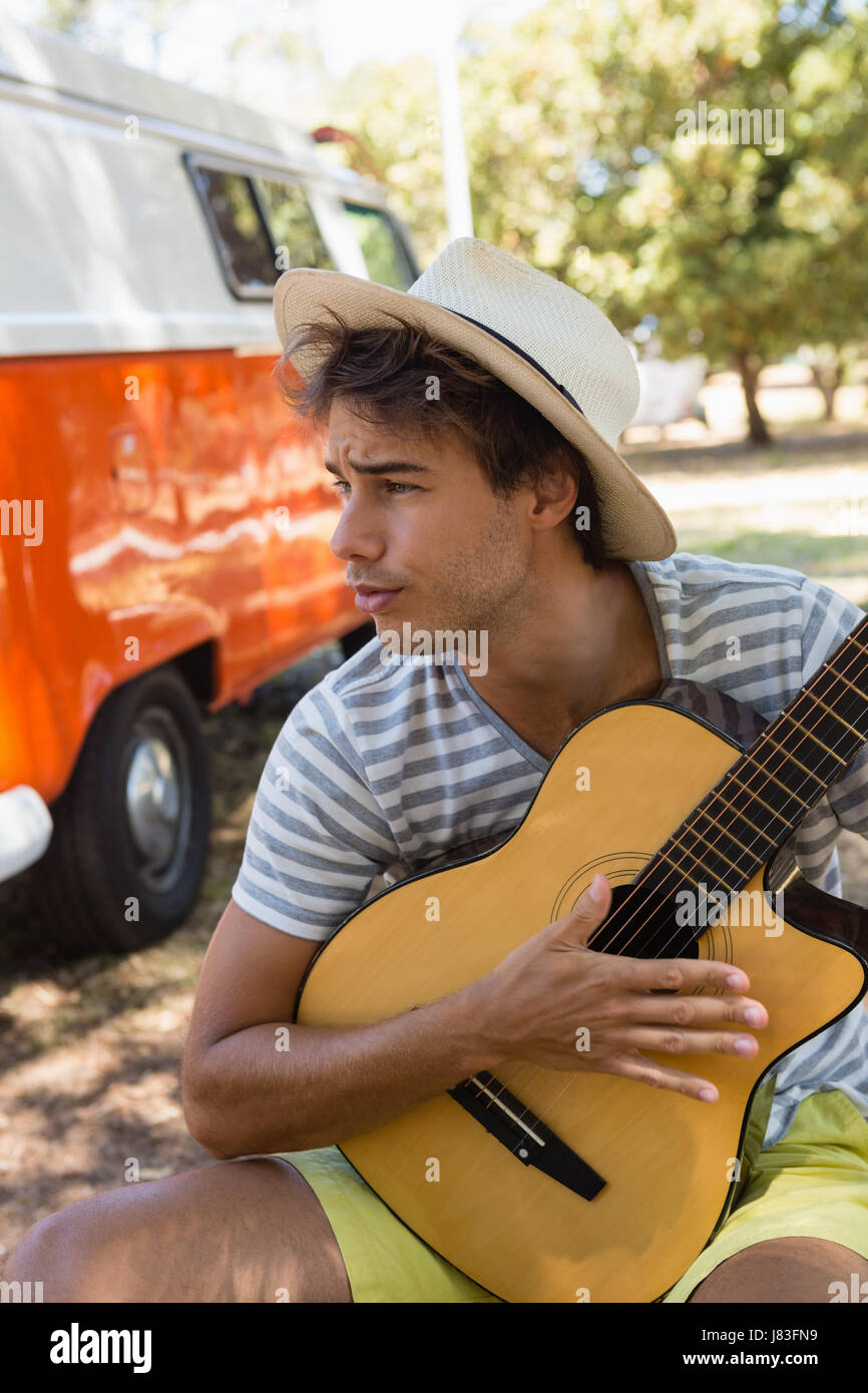 Jeune homme jouant de la guitare dans le parc Banque D'Images