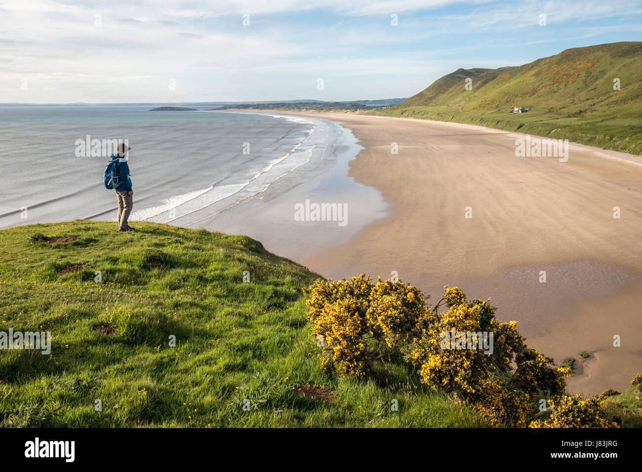 Randonneur femme debout regardant la plage, Rhossili, Gower, Pays de Galles, Royaume-Uni Banque D'Images