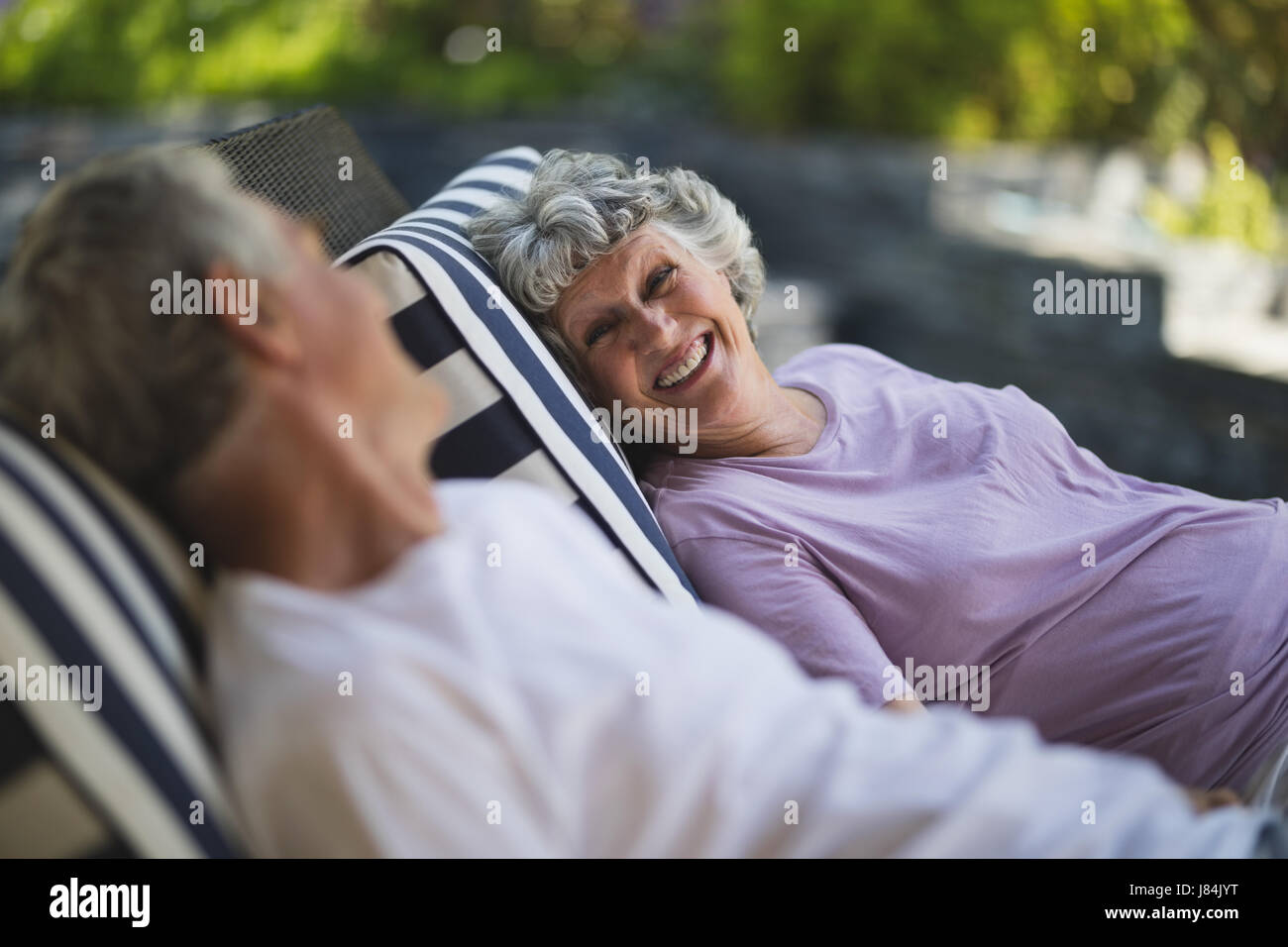 Smiling senior woman looking at man resting ensemble sur des chaises de salon Banque D'Images