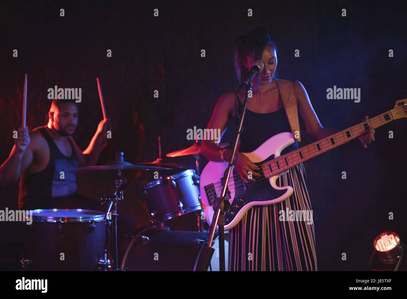 Chanteuse chanter alors que le batteur d'effectuer en boite Banque D'Images