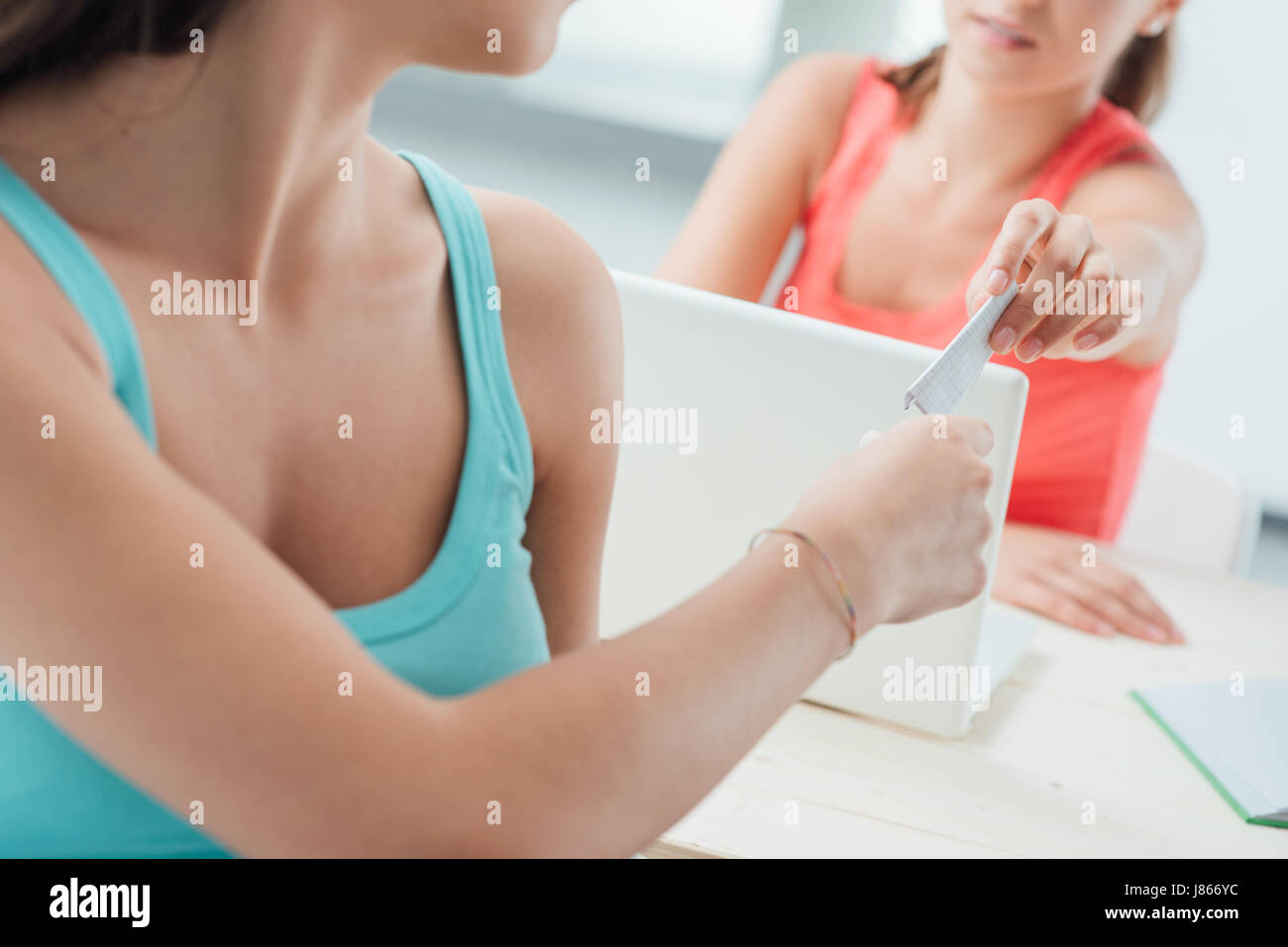 Filles de la classe assis à un bureau et l'adoption d'une feuille de triche, méconnaissable personnes Banque D'Images