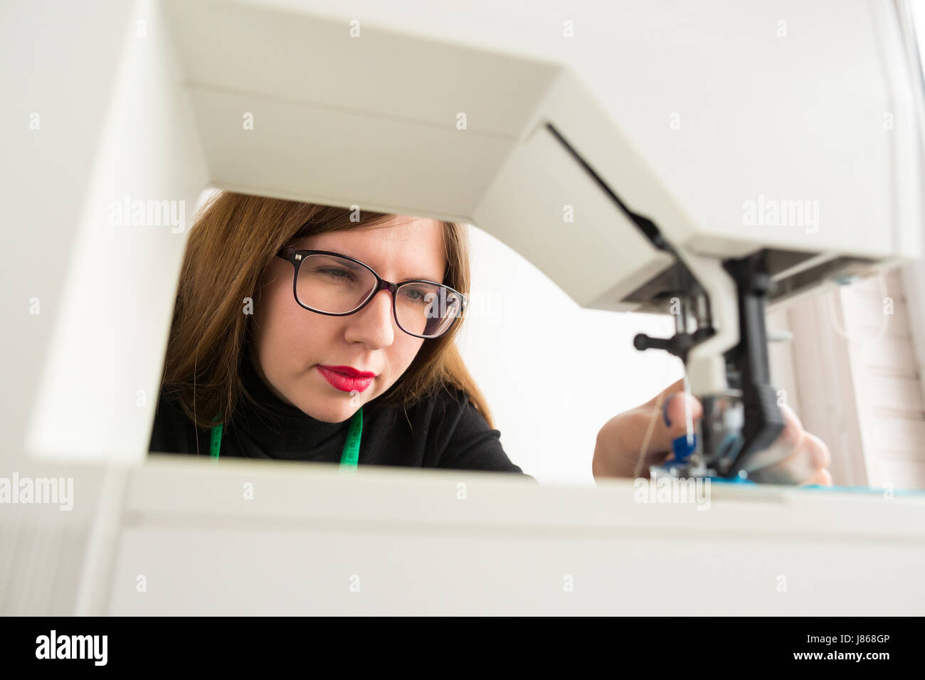 De couture et de quilting à la main dans l'atelier d'un tailleur - belle  femme avec des lunettes au travail sur machine à coudre Photo Stock - Alamy