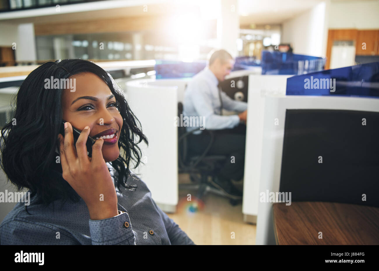 Jolie jeune femme afro-américaine de travail bureau assis et d'avoir une conversation téléphonique. Banque D'Images