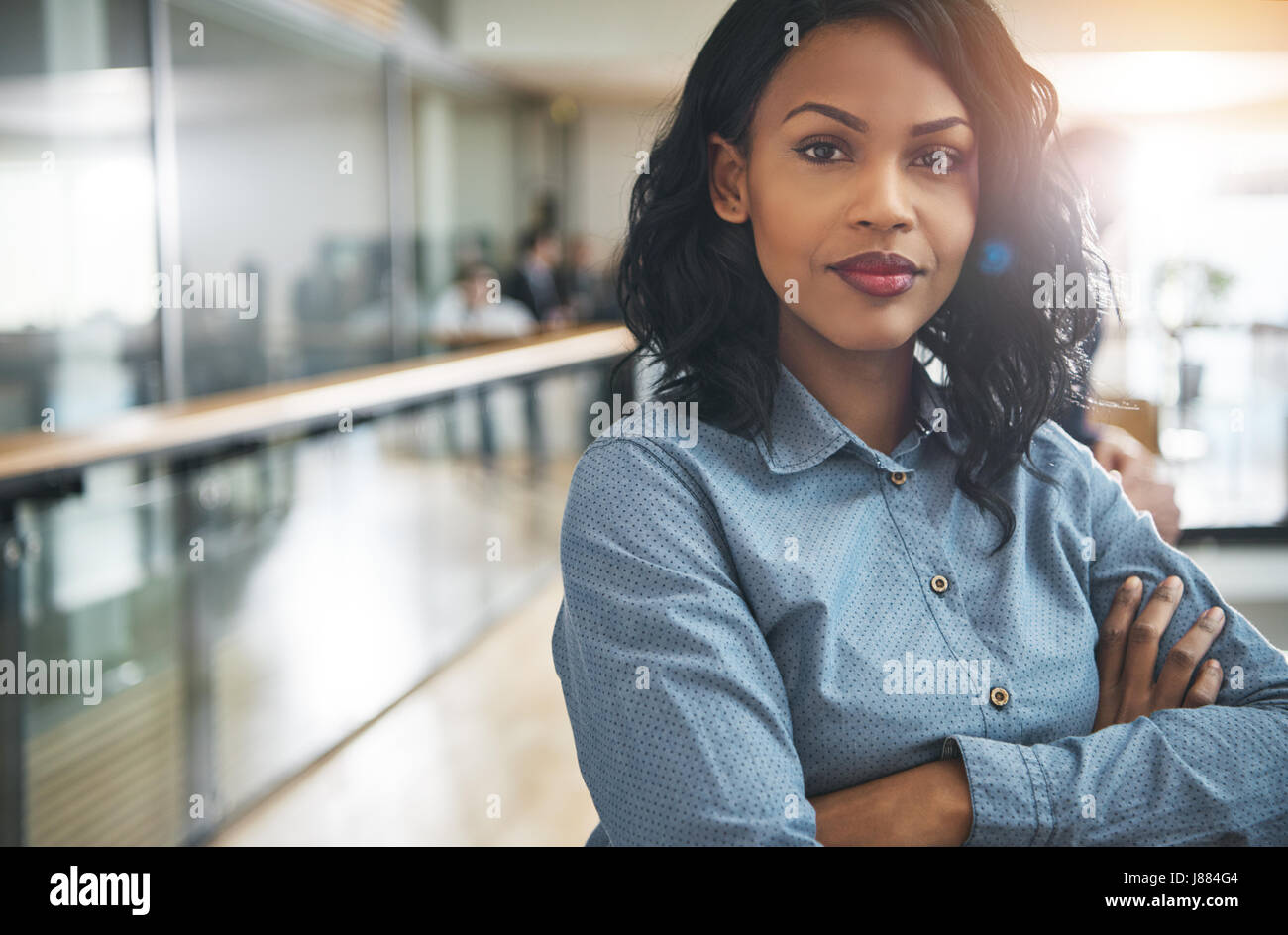 Jolie jeune afro-américaine de rêve office worker standing with arms crossed and looking at camera. Banque D'Images