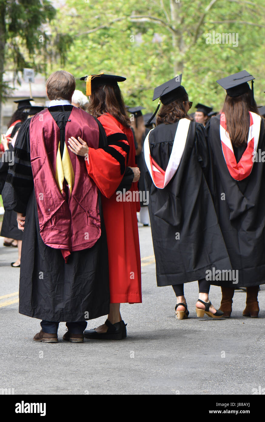Vêtus de robes et chapeaux de l'obtention du diplôme les étudiants et les parents célèbrent la journée. Banque D'Images