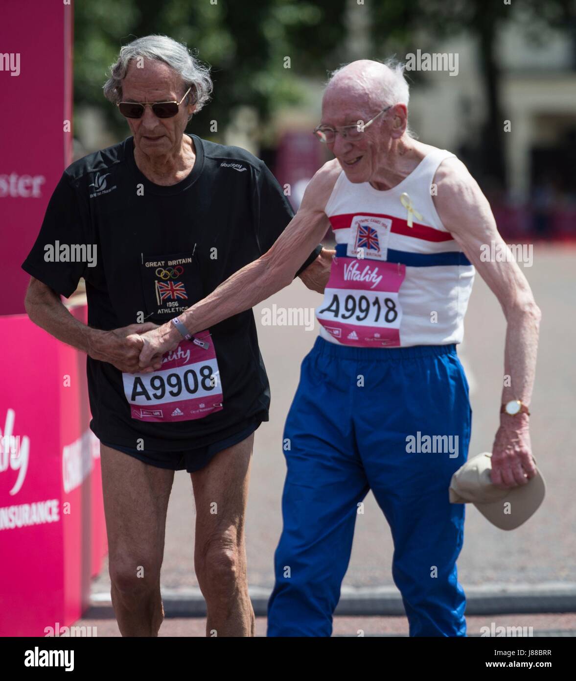 Eric Shirley (à gauche) aide Eric Hall après la finition 'Olympiens Mile' une partie de la vitalité Westminster Mile sur le Mall dans le centre de Londres, avec plus de 100 olympiens y compris en danse sur glace Jayne Torvill légende et de l'aviron d'or olympique Greg Searle prendre part. Banque D'Images