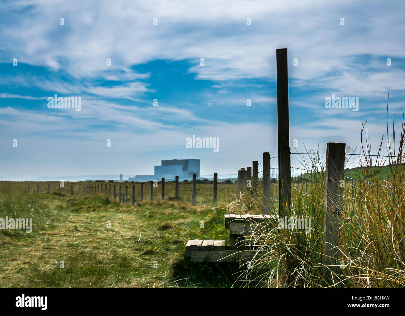 Vue au niveau du sol le long de John Muir Chemin chemin côtier, avec la centrale nucléaire de Torness sur horizon et stile over fence, East Lothian, Scotland, UK Banque D'Images