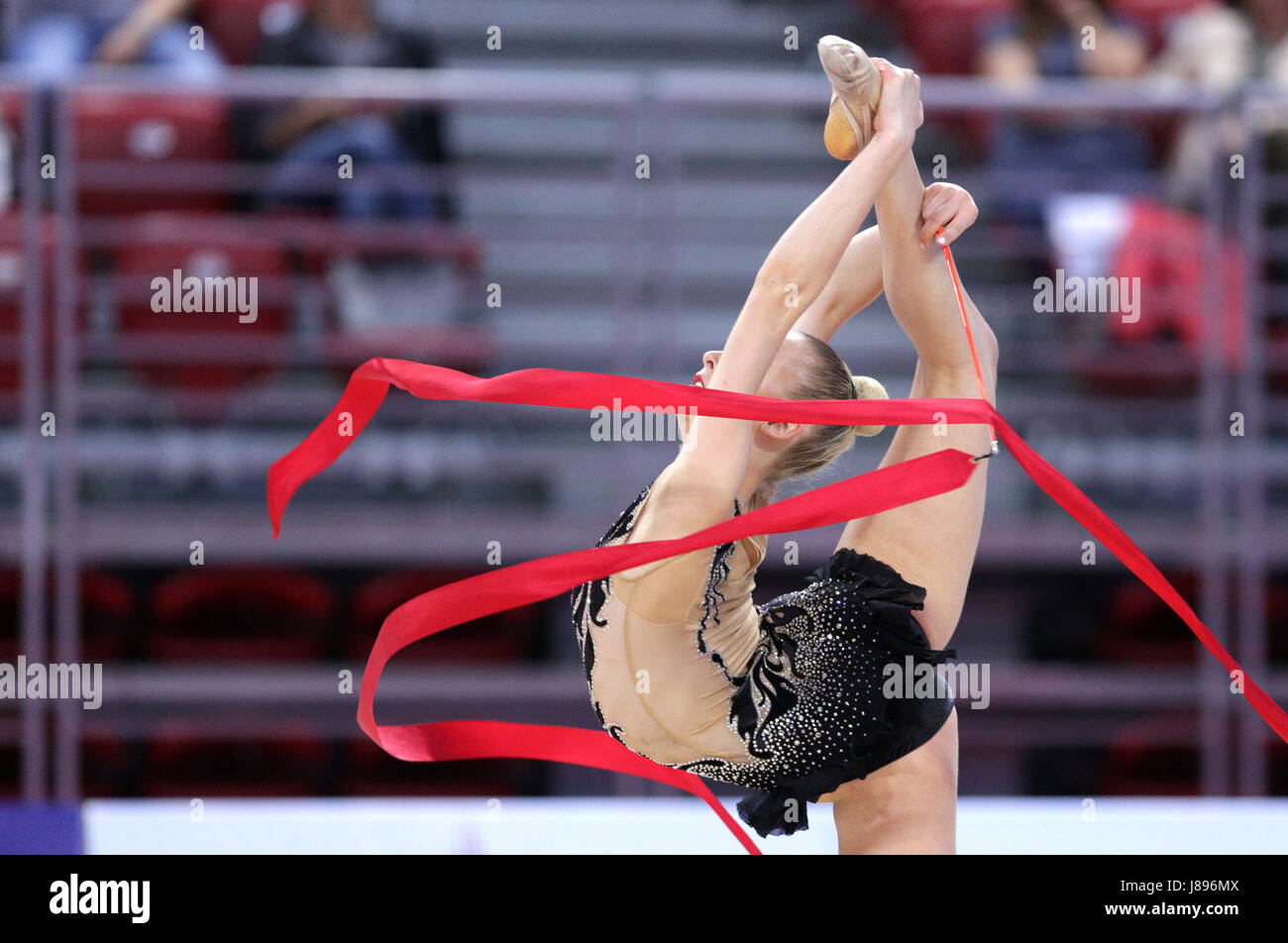 L'athlète de gymnastique rythmique individuel effectue avec le ruban sur l'arène. Les gens méconnaissables. Banque D'Images