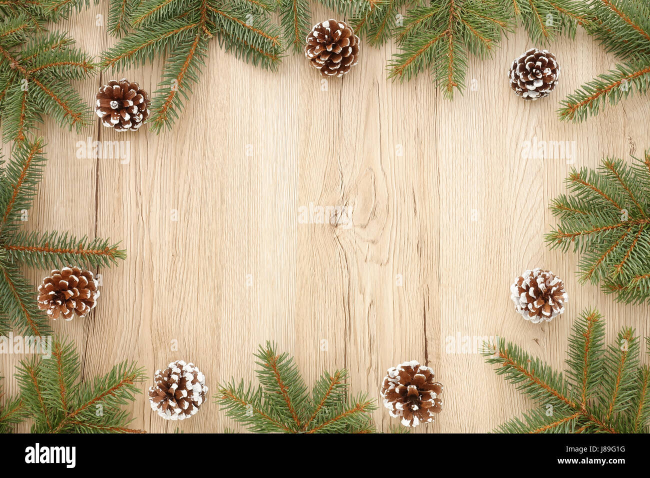 Cadre de Noël de sapin enneigée de brindilles et de pommes de pin sur fond en bois brun avec beaucoup d'espace de copie. Banque D'Images