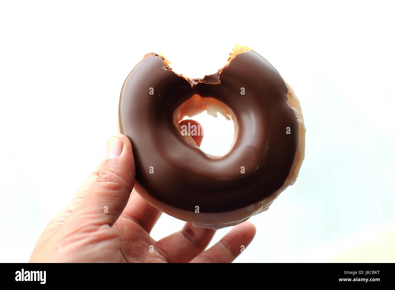 Donut enrobées de chocolat avec bouchée prise hors isolés contre fond blanc Banque D'Images