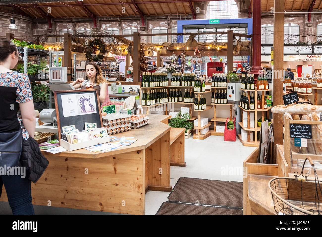 Cusotmer et sales assistant à un blocage de l'alimentation et du vin dans les halles couvertes (marché couvert) à Colmar, Alsace, France. Banque D'Images