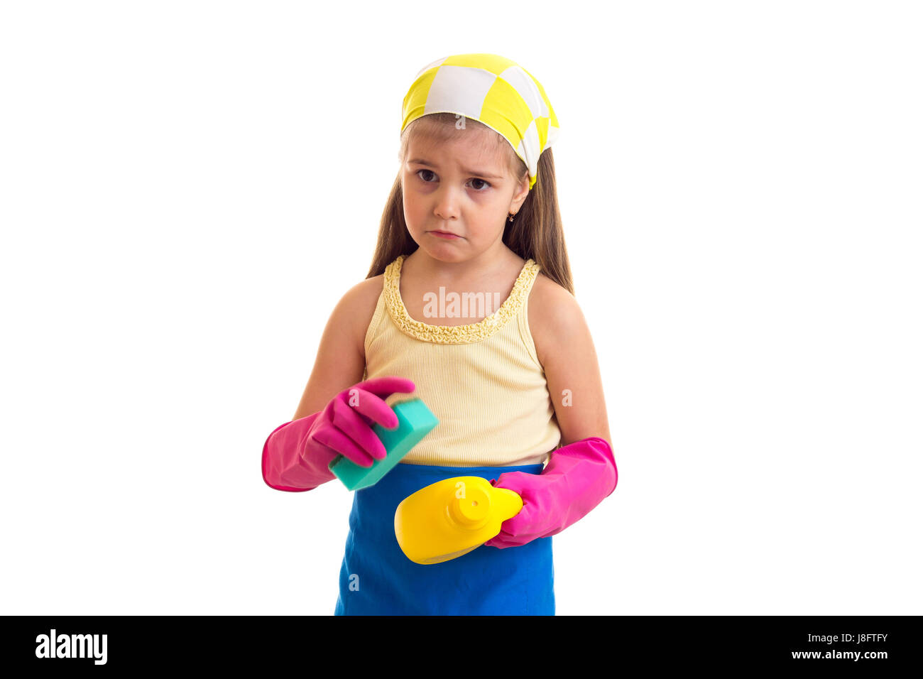 Triste petite fille avec de longs cheveux châtains en chemise jaune et bleu avec des gants et tablier rose jaune foulard vert et jaune éponge holding sur bouteille Banque D'Images