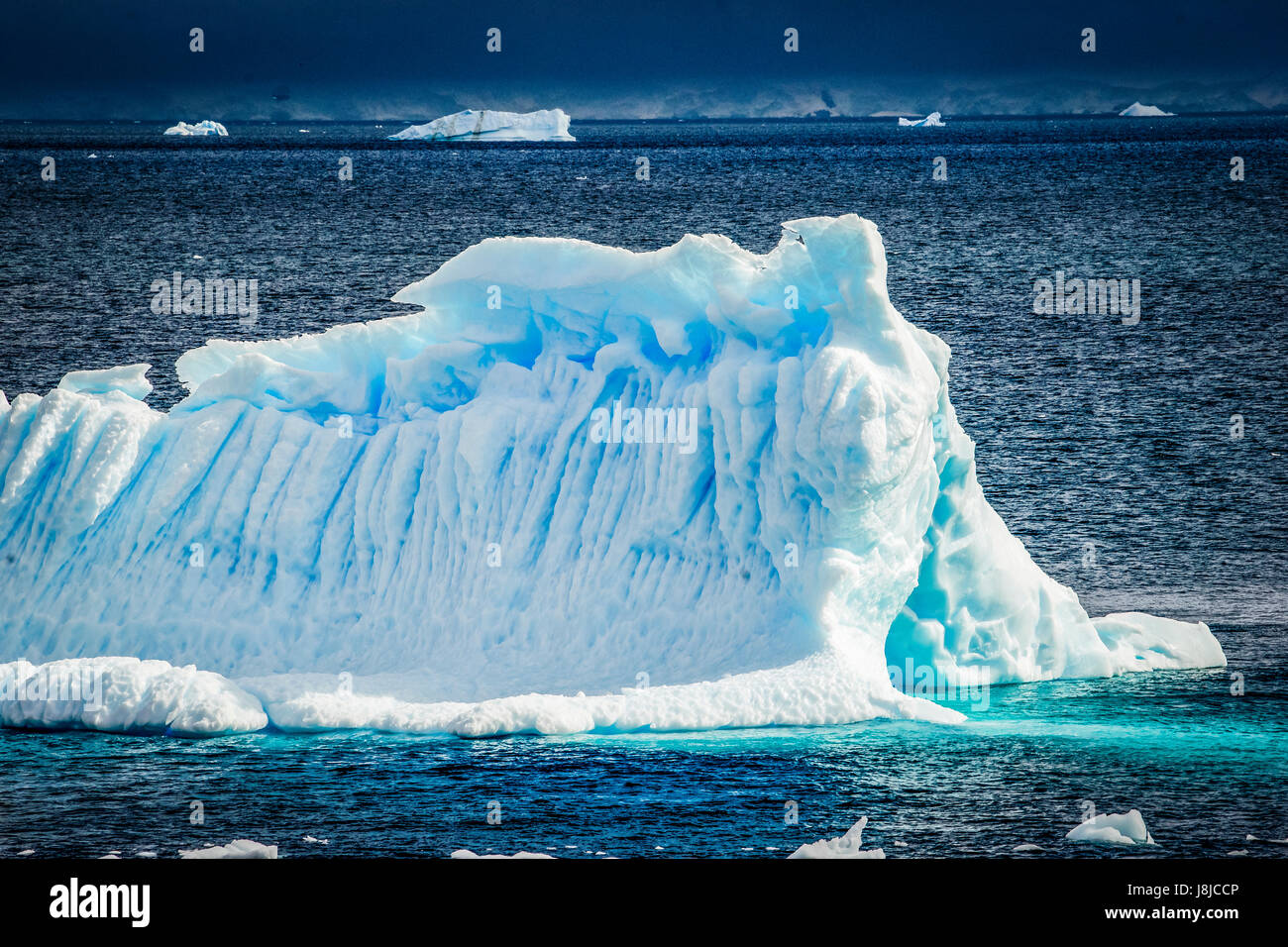 Un rayon de lumière brille directement sur cet iceberg un peu bergy sous un ciel orageux. Banque D'Images