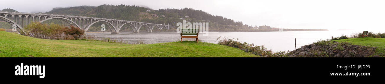 Un banc bien placé se trouve sur le front de mer avec vue sur la traversée de pont Banque D'Images