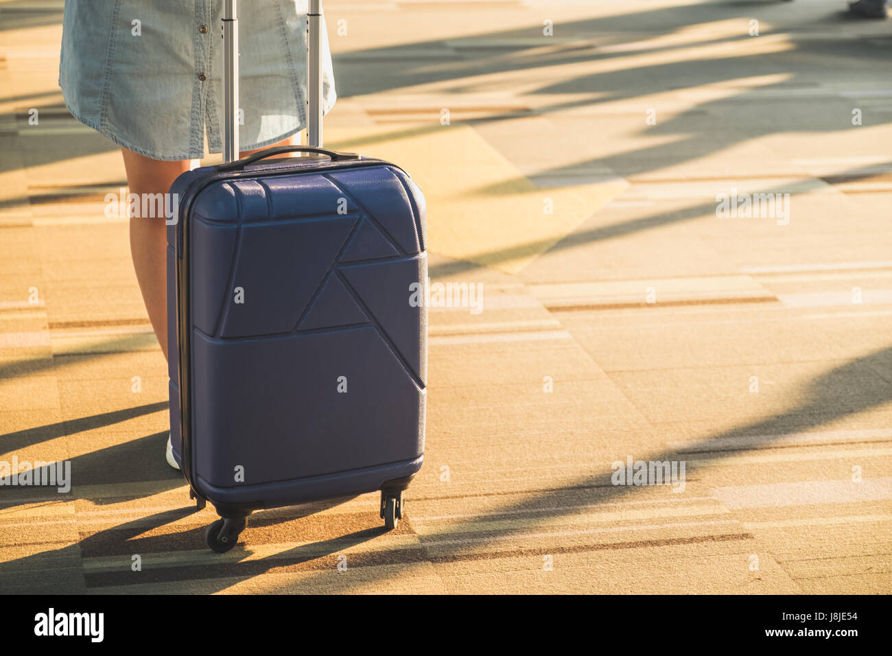 Jeune femme porter des chaussures blanches avec valise voyage permanent avec la lumière du soleil du matin à travers la vitre à l'aéroport,Vacances. Banque D'Images