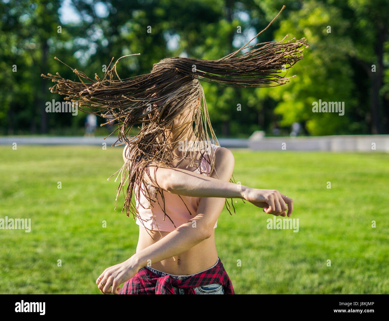 Girl avec zizi dreadlocks cornrows dancing on lawn Banque D'Images