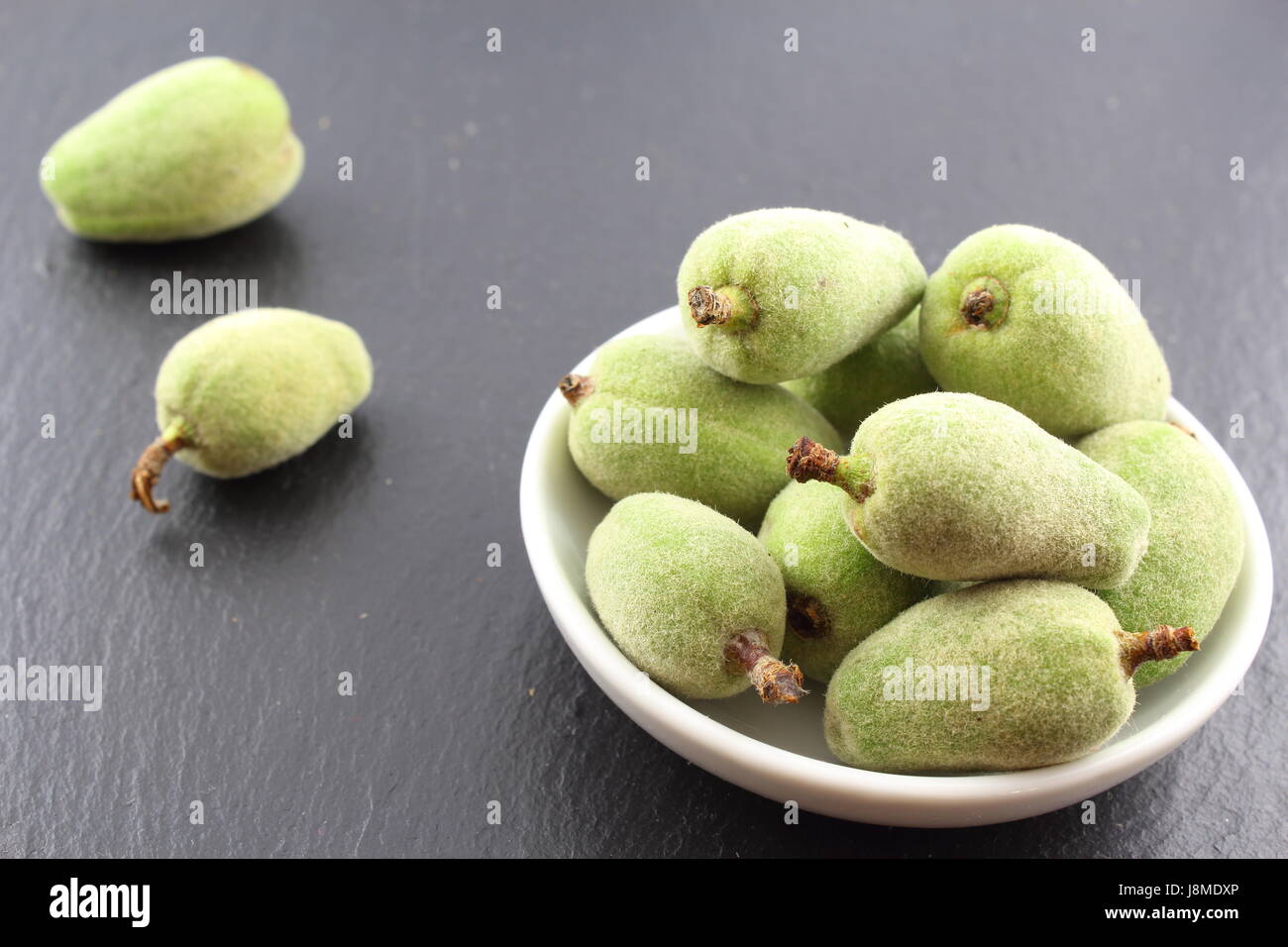 Composition de fruits amande verte fraîche dans un petit bol blanc Banque D'Images