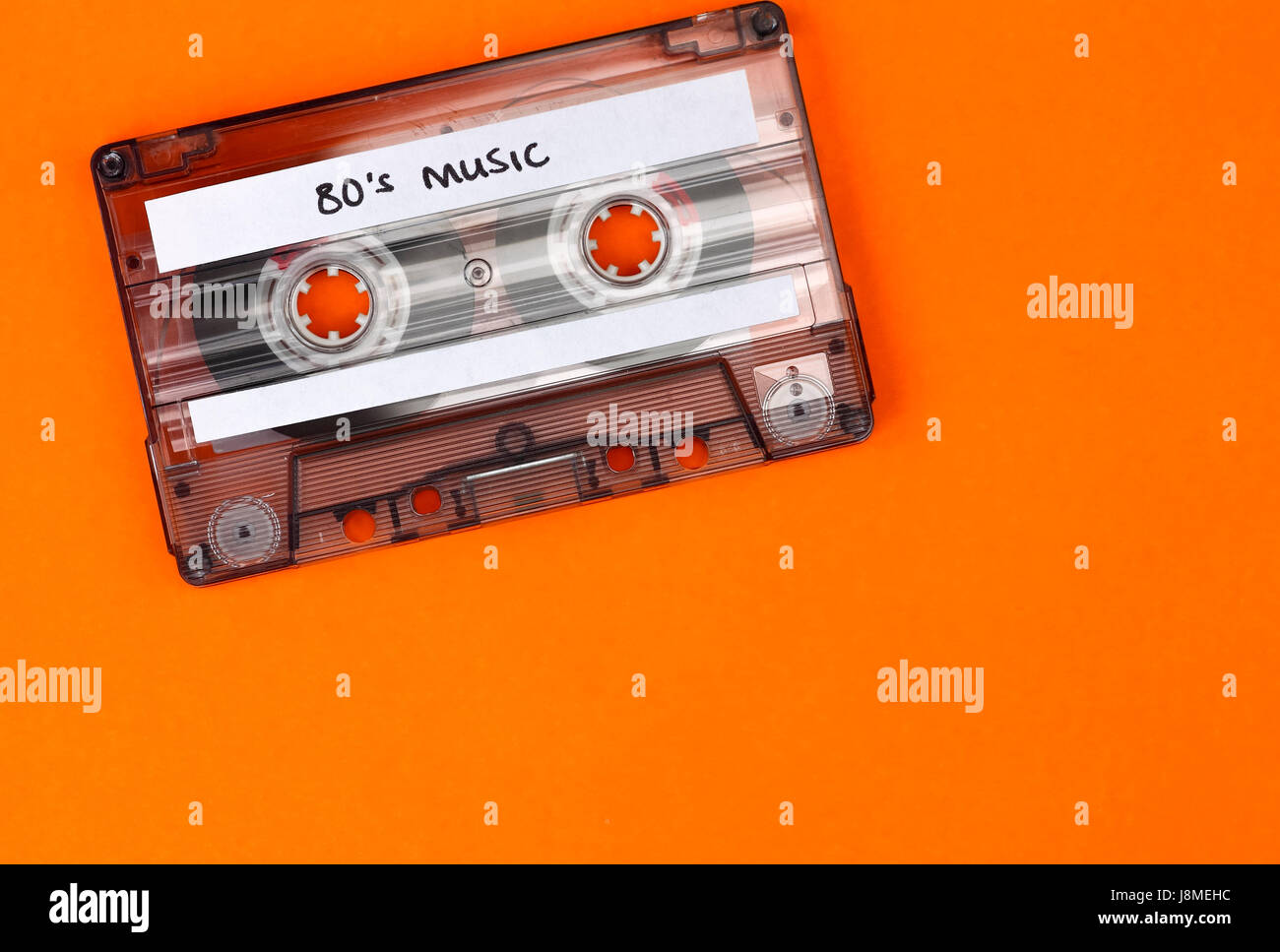 Retro cassette qui a le libellé 80's Music a écrit sur elle et un fond orange Banque D'Images
