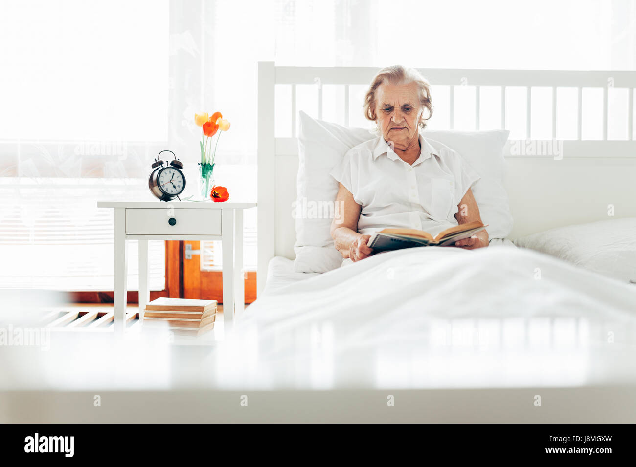 Femme âgée assis confortablement au lit lire son livre préféré à la maison  Photo Stock - Alamy