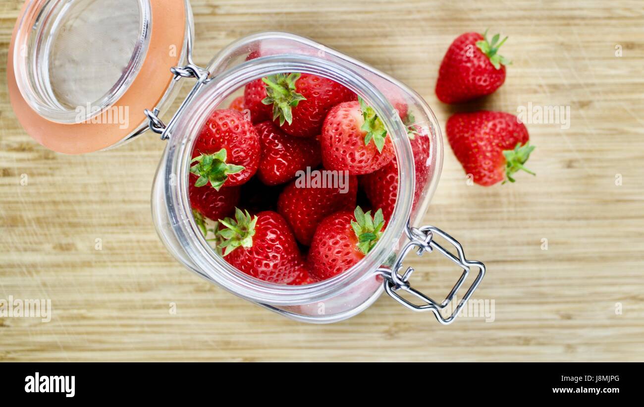 Fraises rouges frais dans une grande cuisine pot sur la planche de bois. Banque D'Images