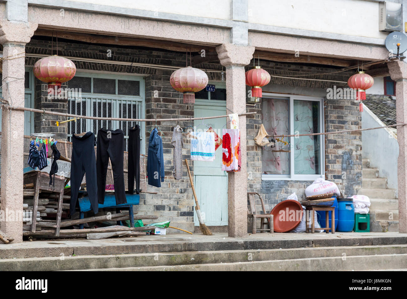 Yuzhong, Zhejiang, Chine. Le séchage des vêtements, des lanternes autour entrée de Maison de village. Antenne Satellite coin supérieur droit. Banque D'Images