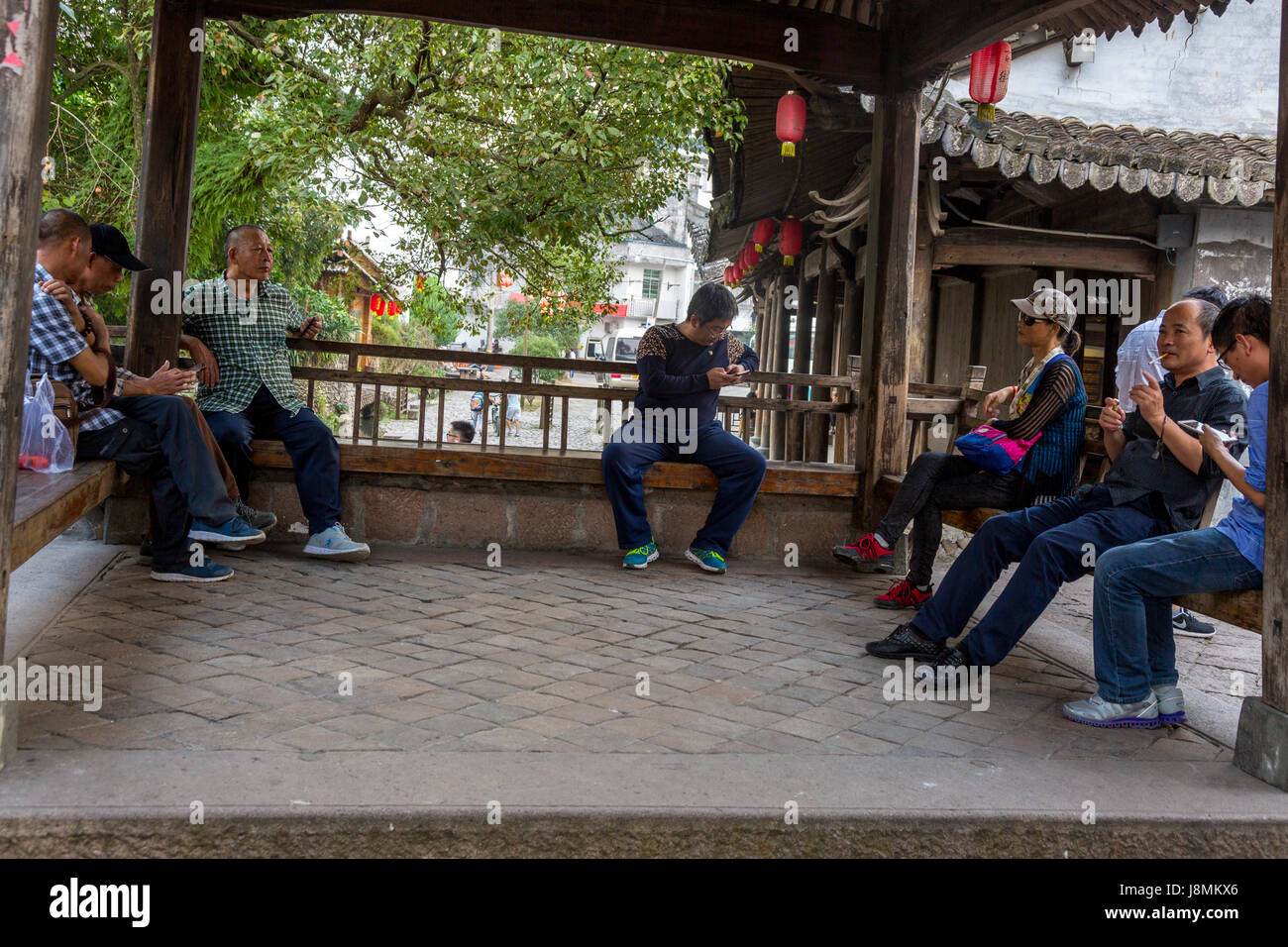 Yantou, Yongjia, Zhejiang, Chine. Hommes parler et contrôler les téléphones cellulaires à un objet Lieu de rencontre. Banque D'Images