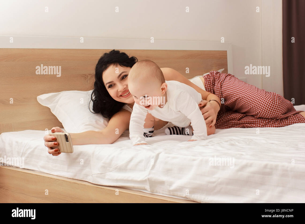 Happy smiling mother and baby lying on bed Banque D'Images